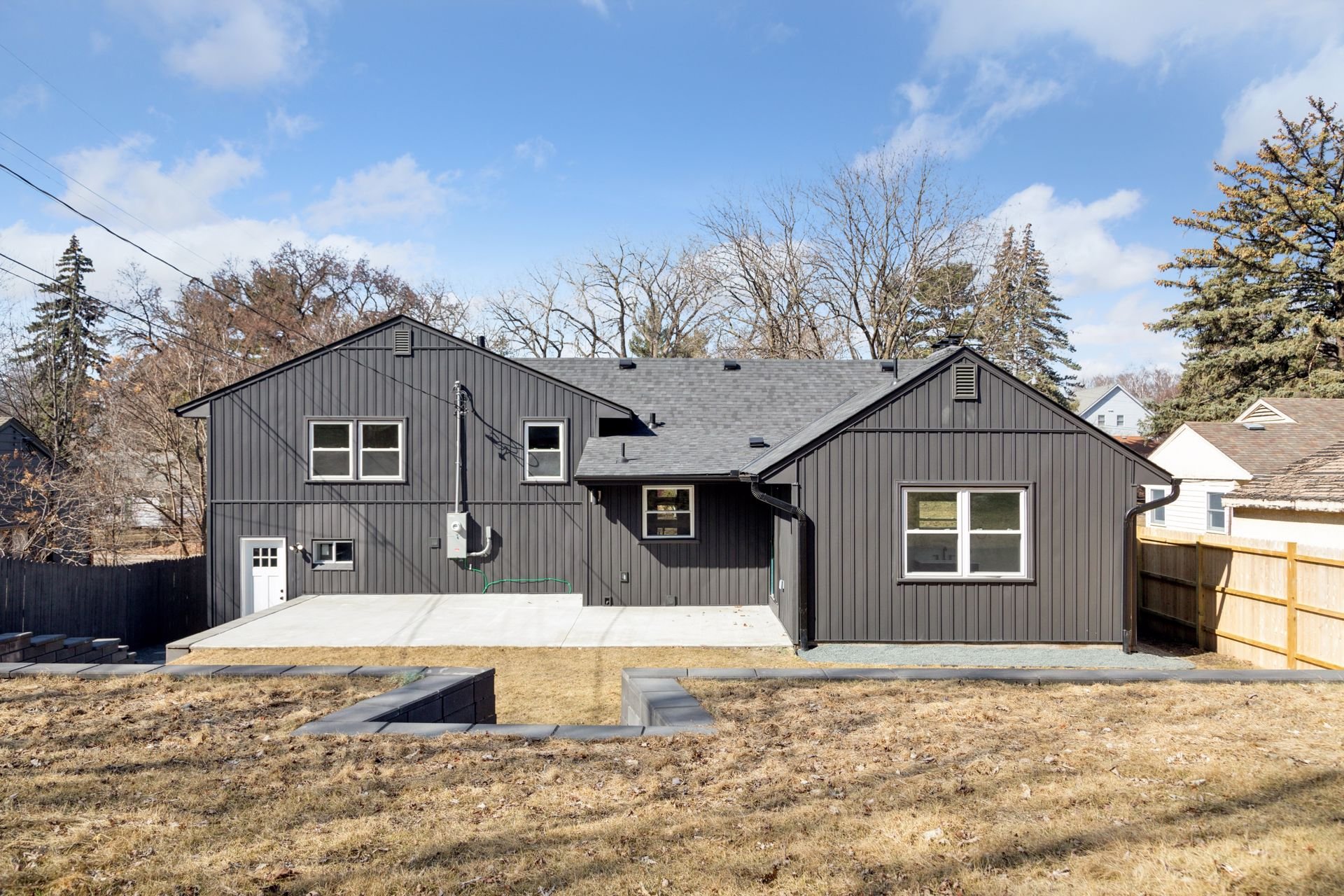 Rear view of a home with a stone patio and retaining walls